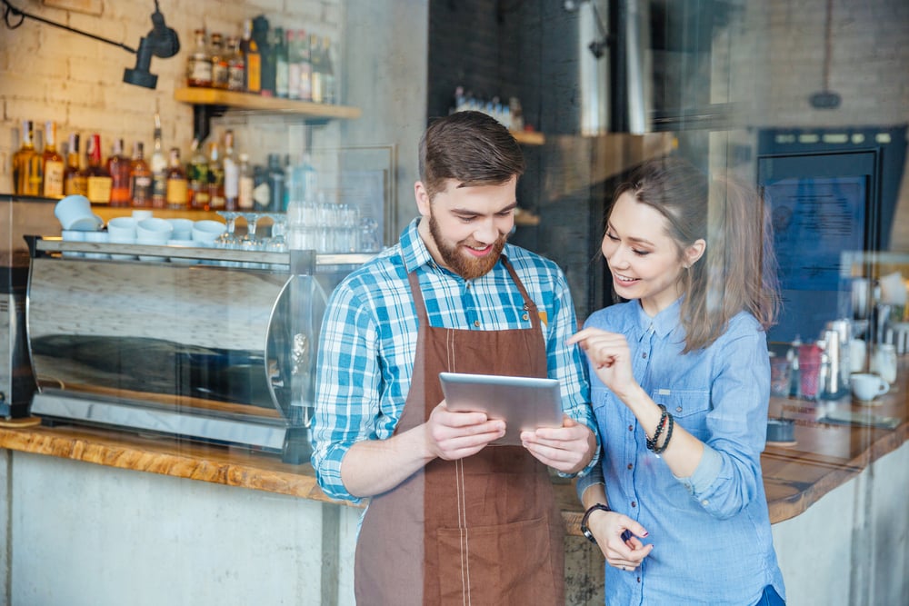 Business owners in Marshall County, Indiana reviewing marketing dashboards and performance results, representing data-driven decision making in a Northern Indiana coffee shop.